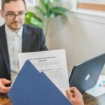 Mortgage broker and client discussing loan application with documents on table.